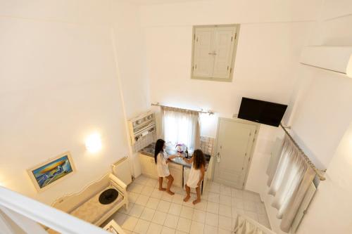 two girls standing in a kitchen with a sink at Erato Apartments in Firostefani