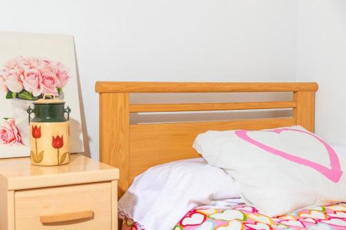 a bed with a vase of pink roses on a table at Cal Soi in Lleida