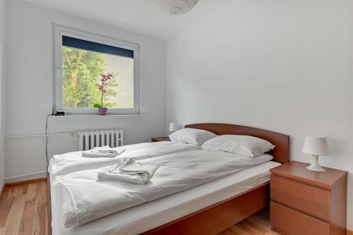 a bedroom with a large white bed with a window at Wave Apartments - Tysiąclecia in Gdańsk
