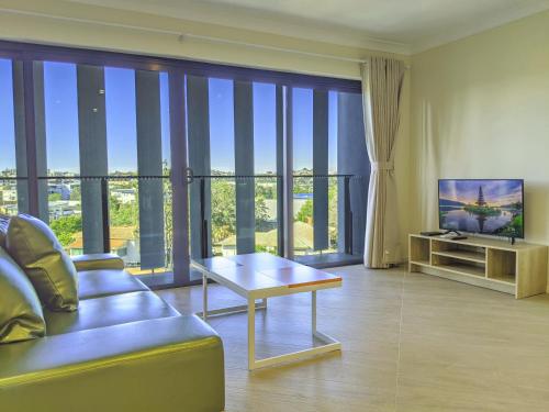 - un salon avec un canapé, une télévision et une table dans l'établissement The Windsor Hotel Rooms and Apartments, Brisbane, à Brisbane