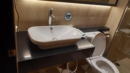 a bathroom with a sink and a toilet at Hotel Polonia Medan managed by Topotels in Medan