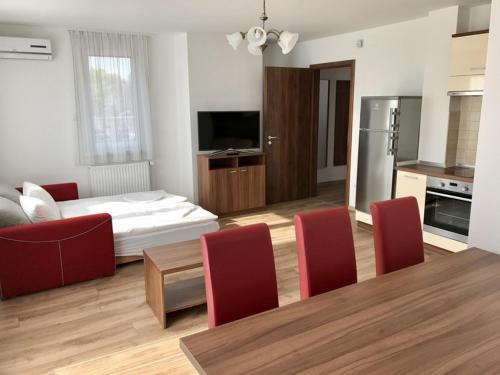 a living room with a dining table and a kitchen at Veritas Apartment Zamárdi in Zamárdi