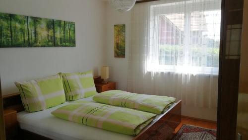 ein Bett mit zwei Kissen und ein Fenster in einem Zimmer in der Unterkunft Haus Luisi in Hitzendorf