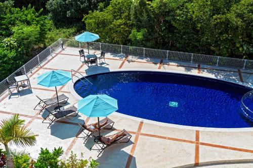 uma piscina com cadeiras e guarda-sóis ao lado em Odysis Onna Resort Hotel em Onna