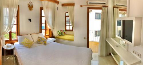 a bedroom with a large white bed and windows at Kekova Hotel in Kas