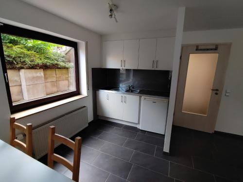 una cocina con armarios blancos, una ventana y una mesa en Ferienwohnung Kerstin Grambow en Vaihingen an der Enz