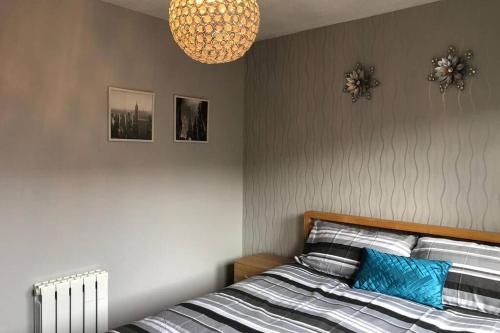 a bedroom with a bed with a blue pillow and a chandelier at Beautiful Self-Catering 2 Bed Apartment with Free Parking 10 Minutes to City Centre in Edinburgh
