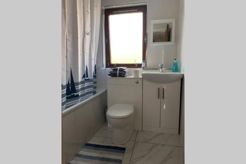 a bathroom with a toilet and a sink and a window at Chic 2 Bed Apartment with Free Parking- Recently Redecorated, 10 Minutes to City Centre in Edinburgh