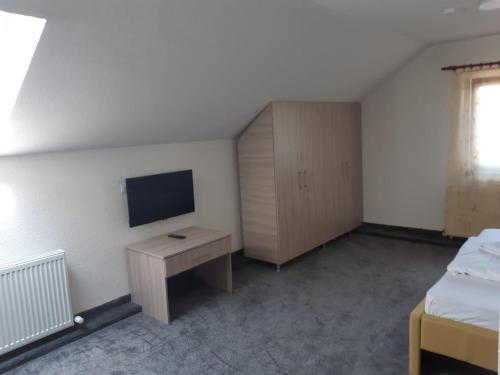 a bedroom with a desk and a tv on the wall at Pensiunea La Gagea in Topliţa