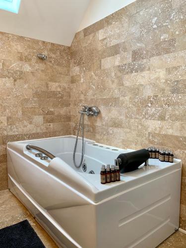 a white bath tub in a bathroom with a tile wall at Hidden Hills Villa in Ţipăreşti