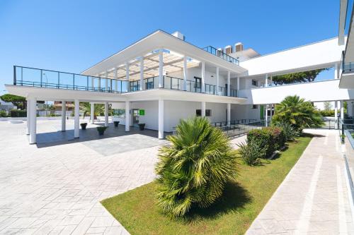 チクラナ・デ・ラ・フロンテーラにあるComplejo Al Sur - by Grupo Tribuのヤシの木が前に立つ大きな白い建物