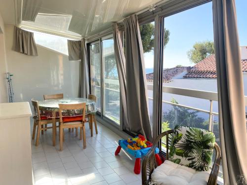 une cuisine avec une table et des chaises ainsi qu'une grande fenêtre dans l'établissement Appartement vue mer le chant des cigales, à Sausset-les-Pins