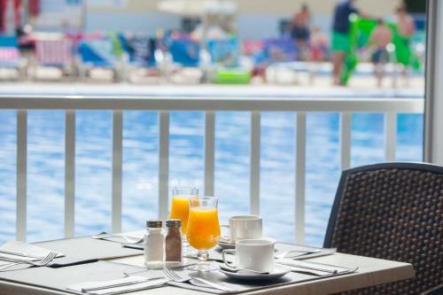 a table with two glasses of orange juice next to a pool at Grupotel Cinco Plazas in Puerto del Carmen