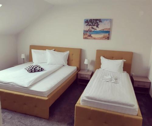 a bedroom with two beds with white sheets at Pensiunea La Gagea in Topliţa