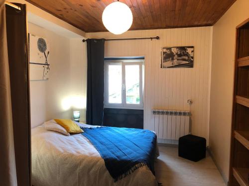 sypialnia z łóżkiem z niebieskim kocem i oknem w obiekcie le petit champliman w mieście Ornans