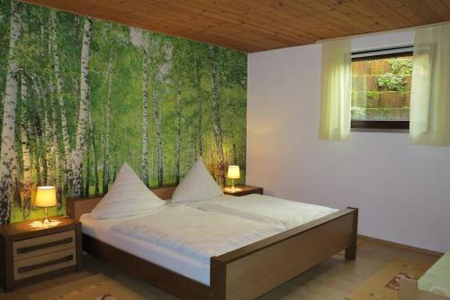 Schlafzimmer mit einem Bett und einem Wandbild von Bäumen in der Unterkunft Ferienwohnung Christina in Hinterweiler