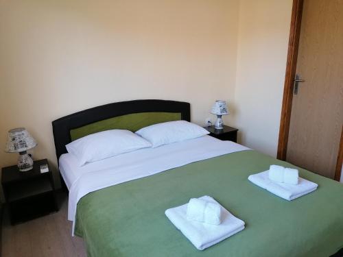 a bedroom with a large bed with two towels on it at Apartmani Sara Trebinje in Trebinje