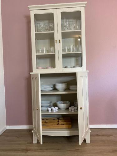 a white cabinet with bowls and dishes in it at Ferienwohnung Birkenhof in Drolshagen