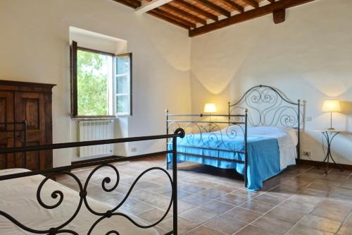 a bedroom with a blue bed and a window at Casa alla Vecchia Posta di Bagno Vignoni in Bagno Vignoni