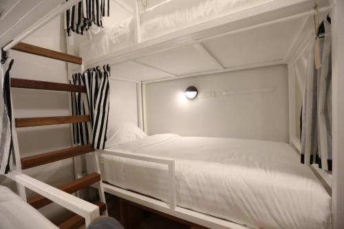a small white bedroom with a bunk bed and a ladder at Hostel Lullaby Non-Smoking in Chiang Mai