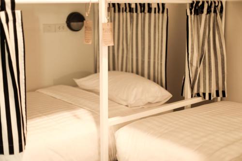 two bunk beds in a room with white sheets at Hostel Lullaby Non-Smoking in Chiang Mai