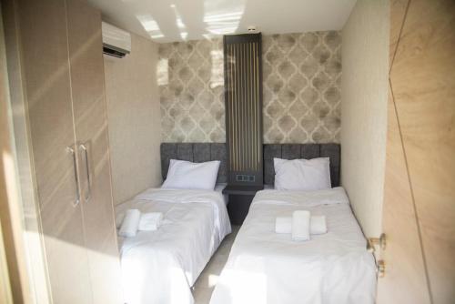 two beds in a small room with white sheets at Le Luxe Suites Hotel & Spa in Bursa