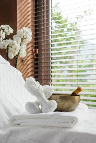 a bowl on top of a bed with towels and flowers at Bio & Wellnesshotel Pazeider - Healing Garden above Meran in Marlengo