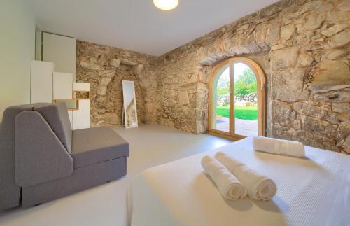 a bedroom with a bed and a chair and a stone wall at Vila Anka in Malinska