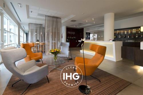 a lobby with chairs and a bar in a store at Holiday Inn Express Antwerpen City North, an IHG Hotel in Antwerp