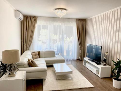 a living room with a white couch and a tv at Die Oase - Luxurious Apartment near the City Center with Free Parking in Bratislava