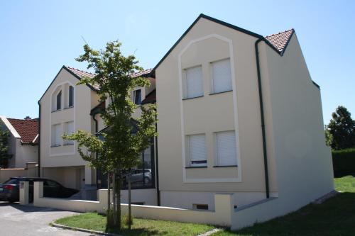 a white house with a tree in front of it at LieblingsOrt in Neusiedl am See