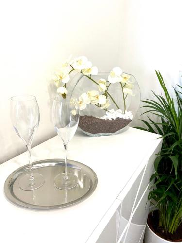 two wine glasses and a vase of flowers on a shelf at Die Oase - Luxurious Apartment near the City Center with Free Parking in Bratislava