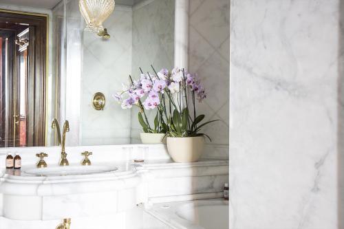 
a bathroom with a sink, mirror, and flowers in it at Bauer Palazzo in Venice
