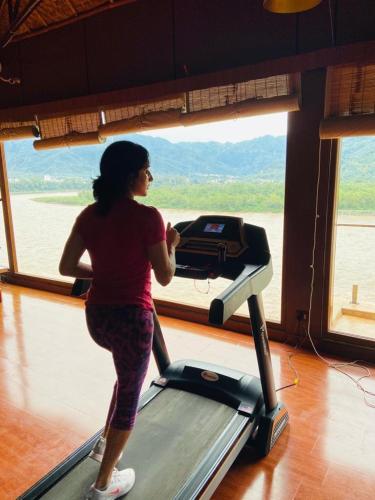 a woman running on a treadmill in front of a window at GANGA KINARE- A Riverside Boutique Resort, Rishikesh in Rishīkesh