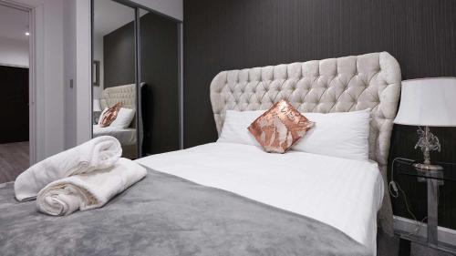 a bedroom with a large white bed with a large headboard at Luxustay Clyde House in Milton Keynes