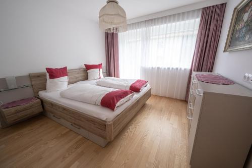 Schlafzimmer mit einem Bett mit roten und weißen Kissen in der Unterkunft Sonnenplatzl-adults only in Fulpmes