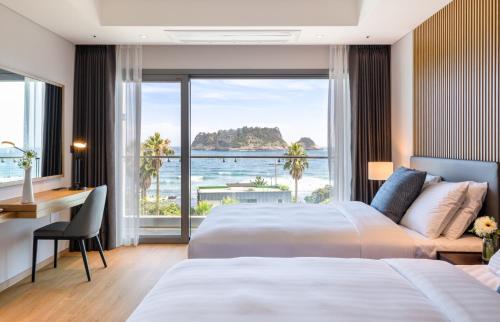 a hotel room with two beds and a desk at The Grand Sumorum in Seogwipo