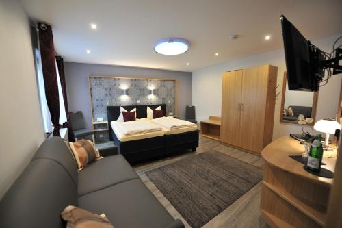 een slaapkamer met een bed, een bank en een televisie bij Hotel-Restaurant Ehses in Zeltingen-Rachtig