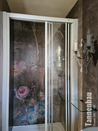 a glass shower in a bathroom with a painting on the wall at The Henry Self Check-In Guesthouse in Zürich