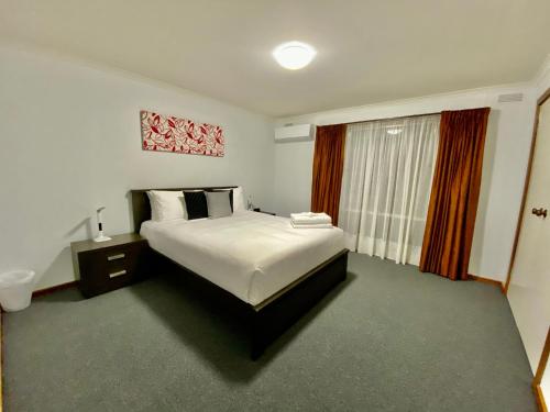 Un dormitorio con una cama grande y una ventana en Sevens Avenue Guest House en Euroa