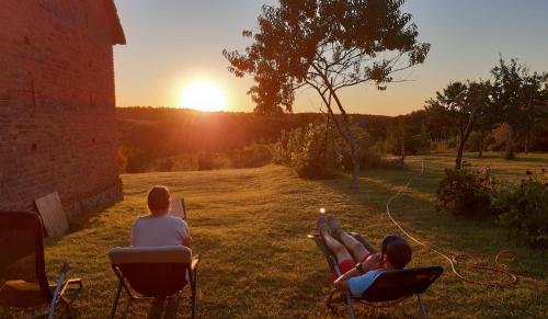 a group of people sitting in chairs watching the sunset at Przystanek Bajka w Puszczy Zielonce in Dąbrówka Kościelna