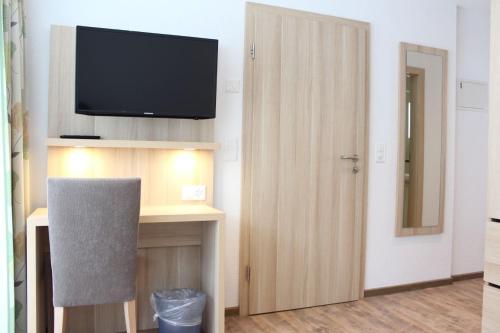 a room with a television and a desk with a chair at Hotel und Appartments Eden in Saas-Grund