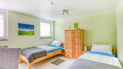 two beds in a room with green walls at Pension zum Rothaarsteig in Netphen