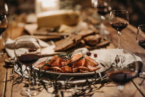 a table with a plate of food and glasses of wine at Casa Krasna Gourmet Boutique Hotel in Lokev