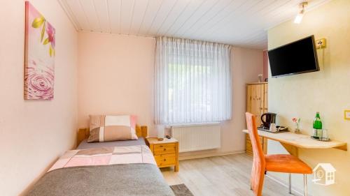 a small room with a bed and a desk and a computer at Pension zum Rothaarsteig in Netphen