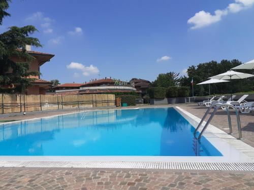 a large blue swimming pool with chairs and an umbrella at Hotel Verri in Misano di Gera dʼAdda