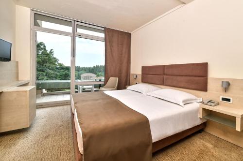 a bedroom with a large bed and a large window at Hotel Mediteran Plava Laguna in Poreč