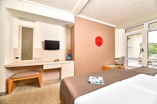 a bedroom with a bed and a desk and a television at Hotel Mediteran Plava Laguna in Poreč