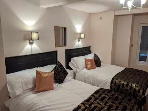 a hotel room with two beds with pillows at Charles Alexander Short Stay - Highcliffe Apartments in Cleveleys