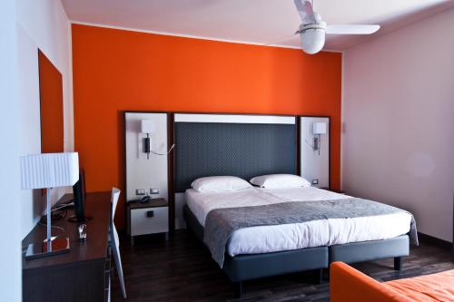 1 dormitorio con 1 cama con pared de color naranja en Hotel Gasparina, en Castelnuovo del Garda